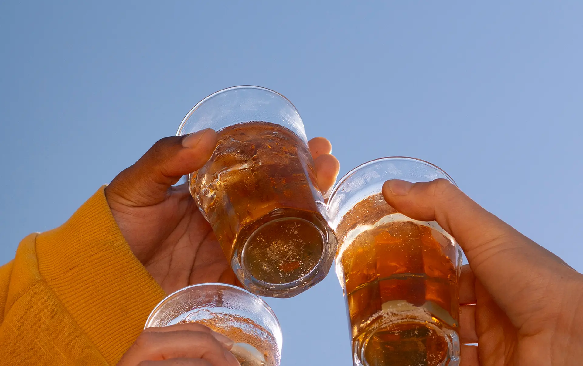 三隻手高舉湧金啤酒對著藍天碰杯