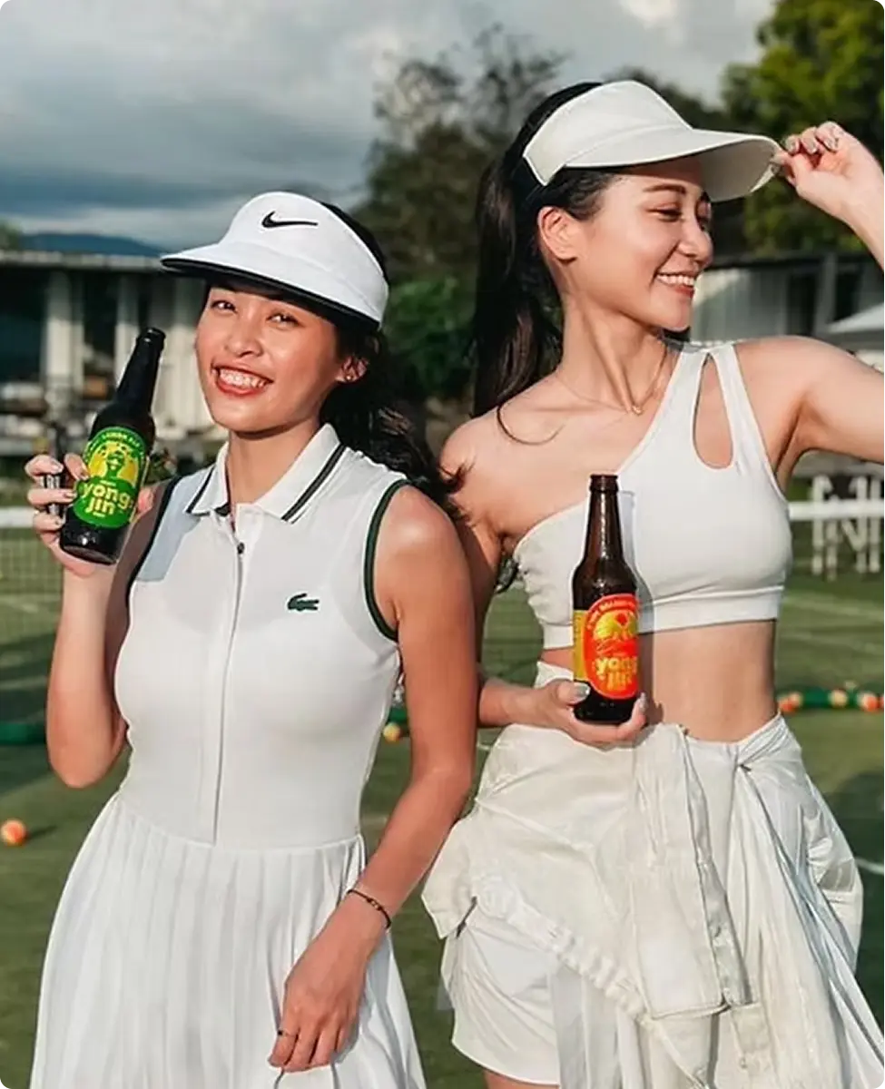 兩位女生在網球場手持湧金啤酒